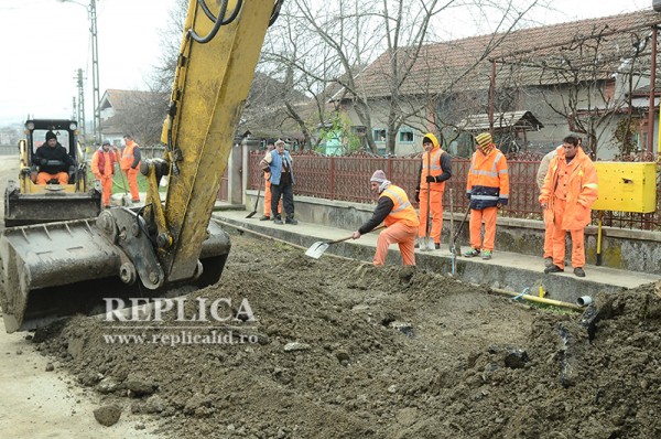 Una dintre cauzele pentru care 80 la sută dintre lucrările de interes public de pe la noi întârzie: se lucrează româneşte. Oare, indivizii din imagine, de lângă gard, n-ar fi avut altceva de lucru, în altă parte, nu să stea să admire forţa excavatoarelor?